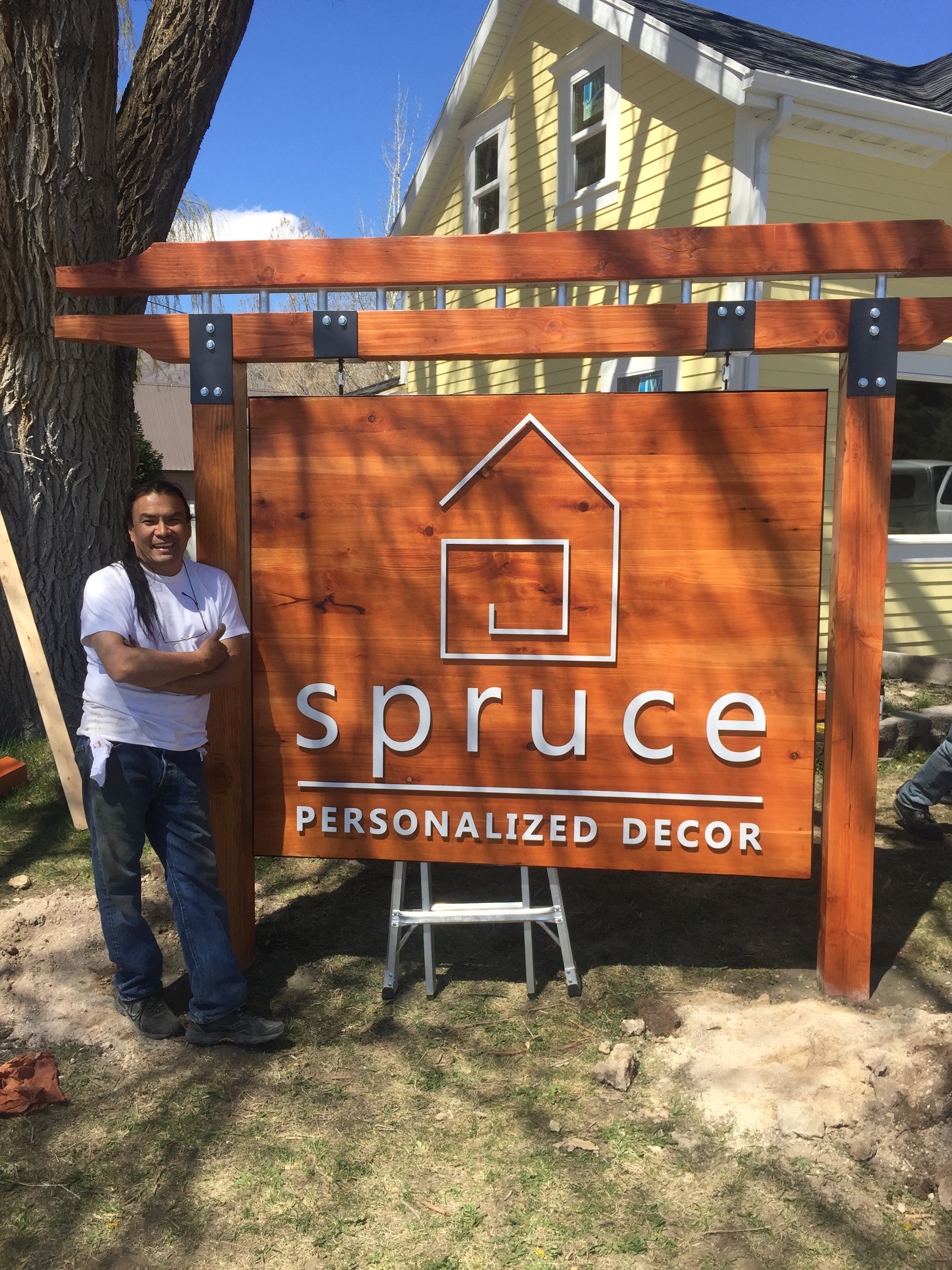 Owner of Seamless Sign Services standing next to newly installed wood sign